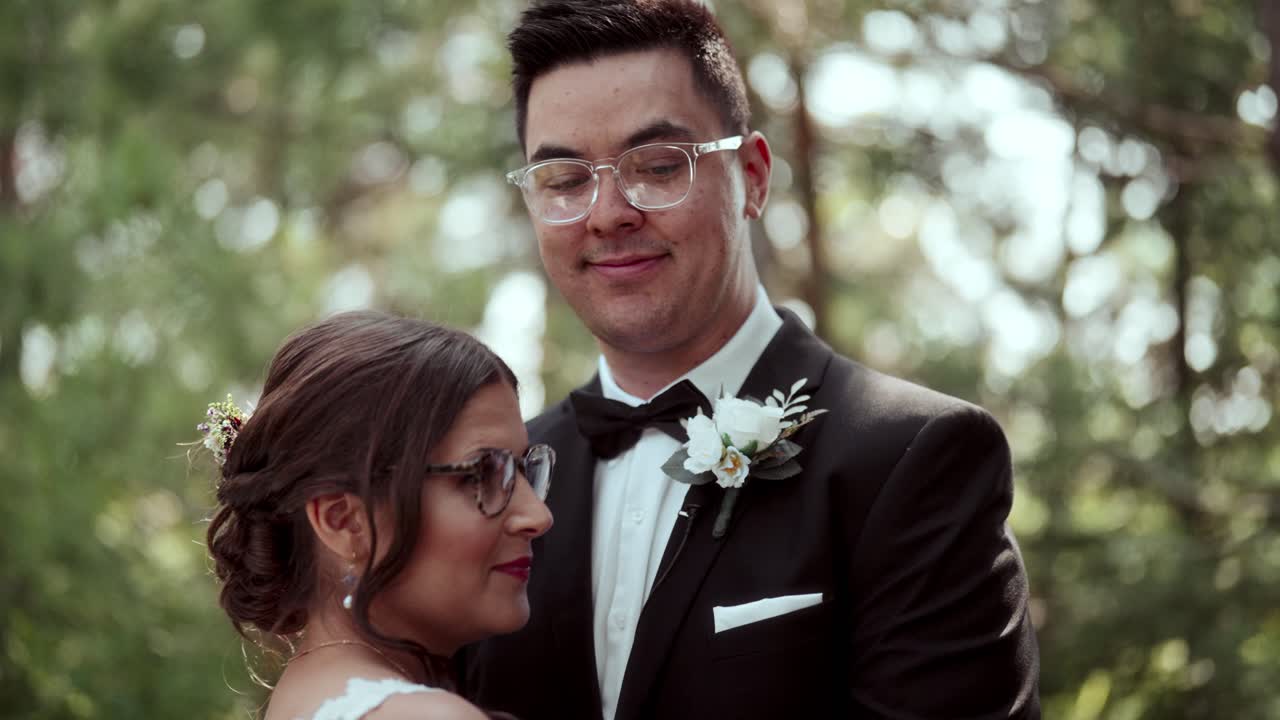 Documentary handheld: couple kiss in woods; camera tilts up to reveal his smile
