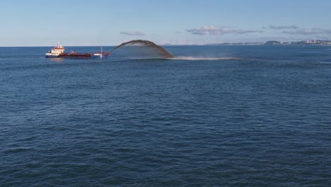 a dredging ship pumps sand into the ocean, restoring cyclone-damaged areas near surfers paradise, gold coast