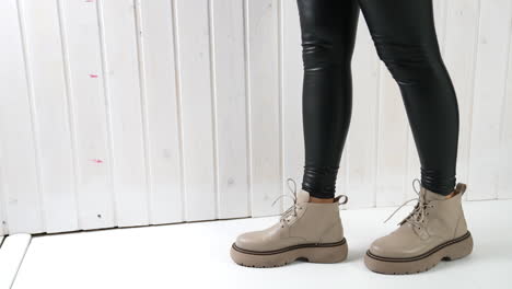 comfortable leather beige boots on a girl in black leggings. lady dances to show the beautiful and modern footwear.