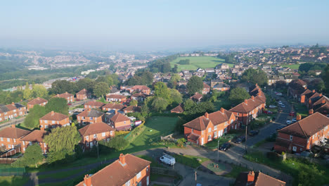 Un-Dron-Captura-La-Finca-Municipal-De-Dewsbury-Moore-En-El-Reino-Unido,-Destacando-Las-Casas-De-Ladrillo-Rojo-Y-El-Paisaje-Industrial-De-Yorkshire-En-Una-Mañana-Soleada.