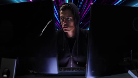 Animation-of-caucasian-male-hacker-over-pink-and-blue-neon-light-trails