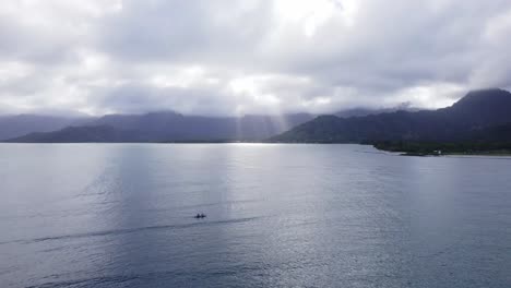 a peaceful scene of paddlers on calm waters, with majestic mountains and sun rays breaking through the clouds in the background