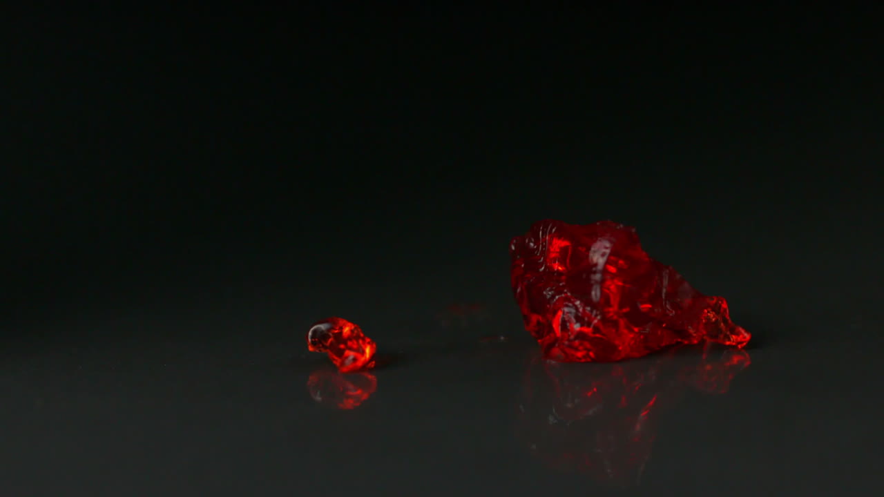 gelatina roja cayendo y rebotando sobre un fondo negro