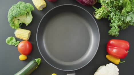 Video-of-fresh-vegetables-around-frying-pan-with-copy-space-on-grey-background