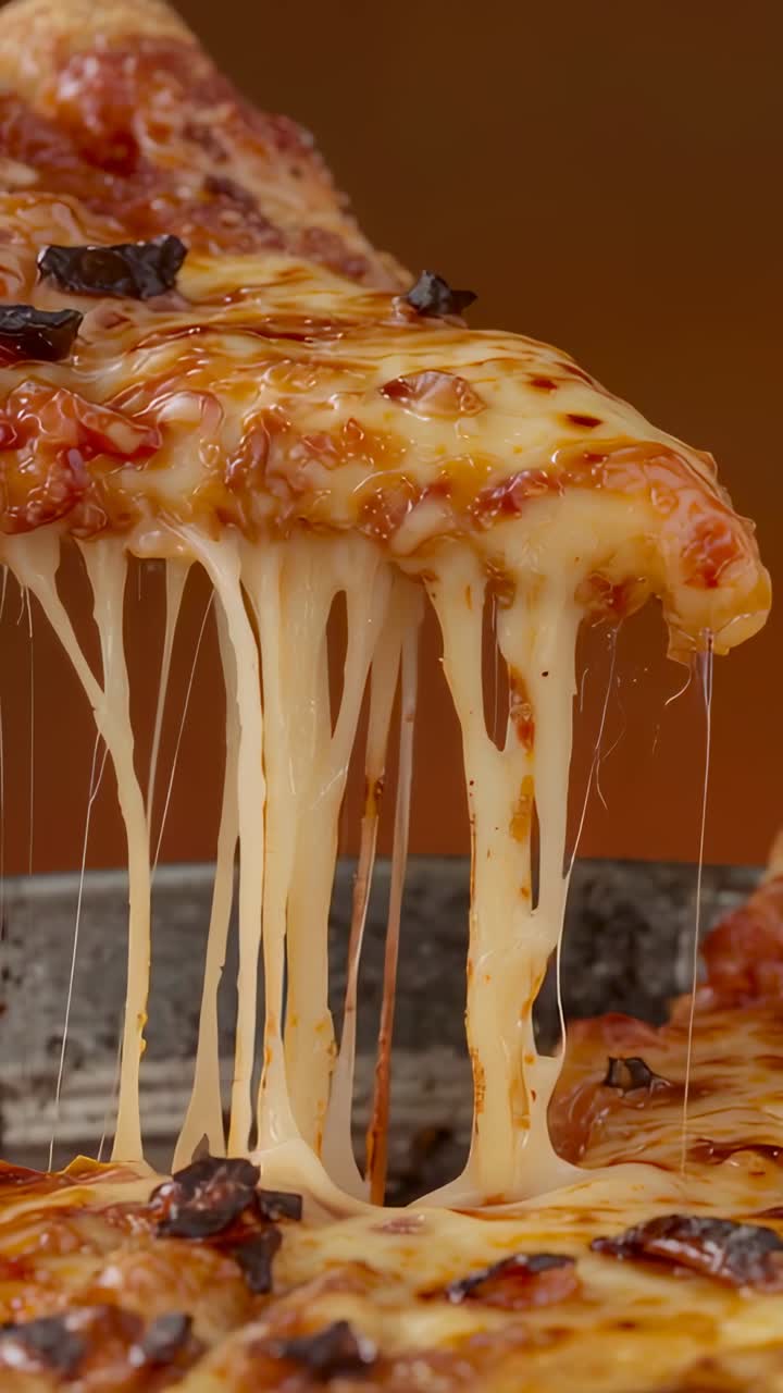 Video verticale: una fetta di pizza viene sollevata da una teglia in metallo, mostrando fili di formaggio fuso