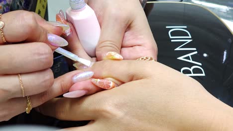 nail art technician performing manicure painting at beauty salon - hands closeup