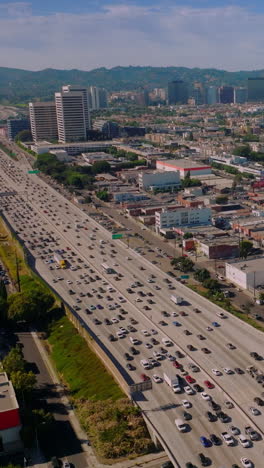 beautiful sunny panorama of lively american city. busy traffic on roads of los angeles from aerial perspective. hills at backdrop. vertical video