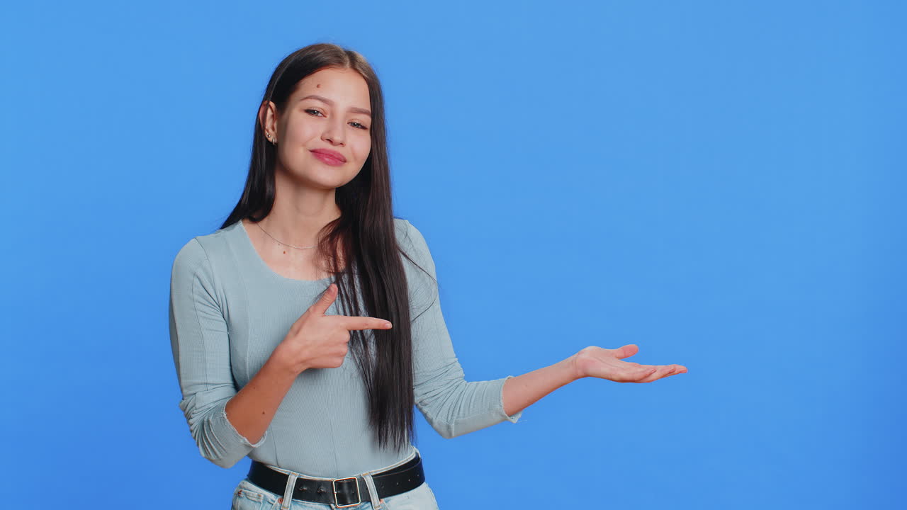 mujer joven mostrando los pulgares hacia arriba y apuntando a la derecha en el espacio en blanco lugar para su logotipo de publicidad