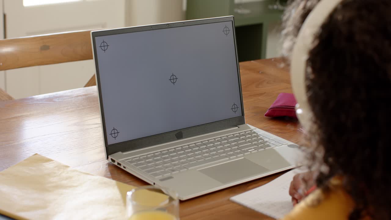Studerende tager en rød blyant og læner sig frem for at tage noter, mens de studerer på en sølvfarvet laptop.