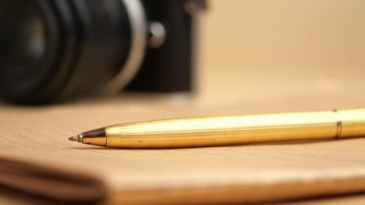 Pen, Camera, and Notebook on a Desk