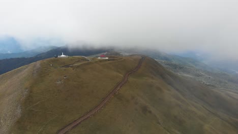 Drone-video-over-foggy-mountain-monument-Gramos-dirt-gravel-roads-Gkesos-peak