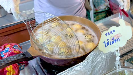 vendor frying sweet potato balls at bangkok floating market stall