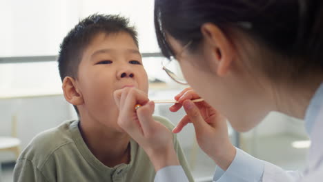 doctor checking throat of asian boy
