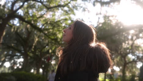 portrait of beautiful young hispanic woman looking up at the trees in the park outside on a sunny afternoon, latina, back lit, proud, nature, surroundings, fresh air, healthy, vitality