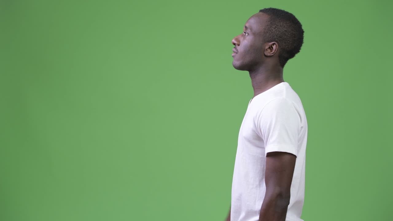 Profile view of young African man against green background