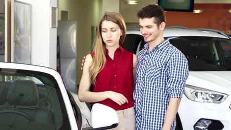 una pareja amorosa examinando un nuevo descapotable para la venta en el concesionario