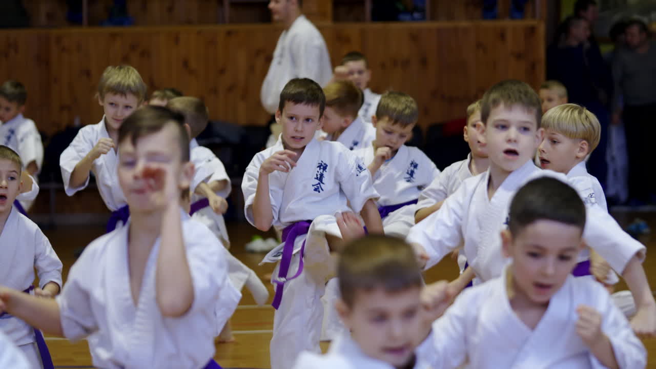 Working hard during karate training. Teenage boys in white kimonos practicing kicks. Blurred foreground.