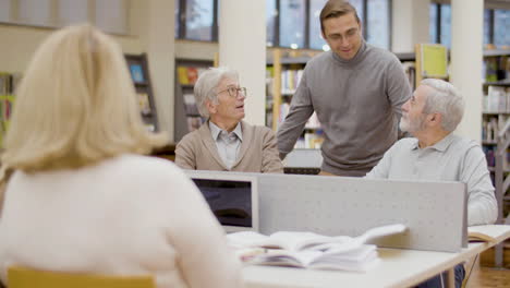 Profesor-Hablando-Con-Personas-Mayores-Que-Estudian-En-La-Biblioteca.