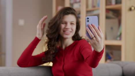 young dark-haired woman fixes hair and takes selfie with phone at home