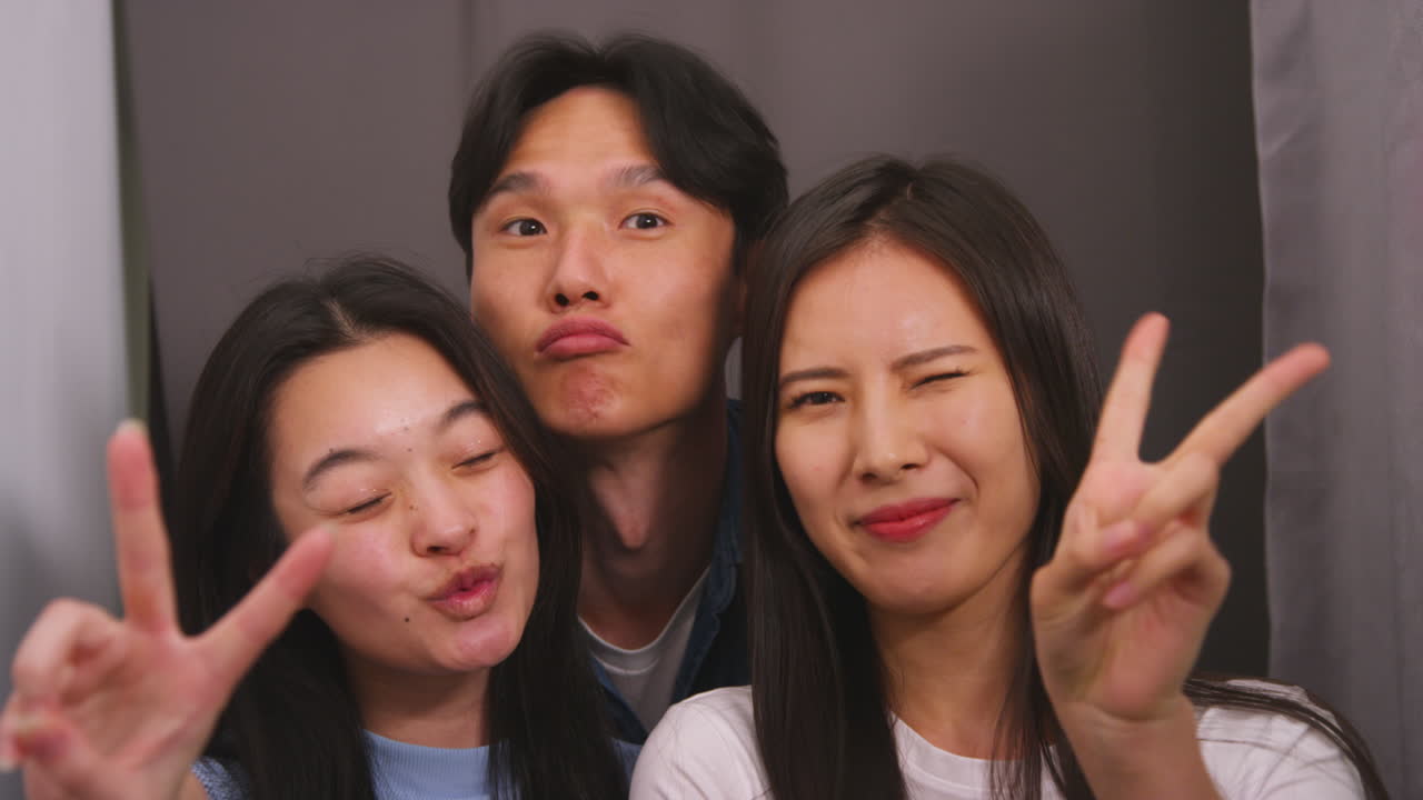 Group Of Friends In Photo Booth Having Fun Posing For Portrait And Pulling Faces Shot In Real Time 1