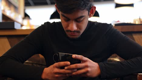 Thoughtful-Sri-Lankan-man-sitting-with-cup-of-coffee,-front-view