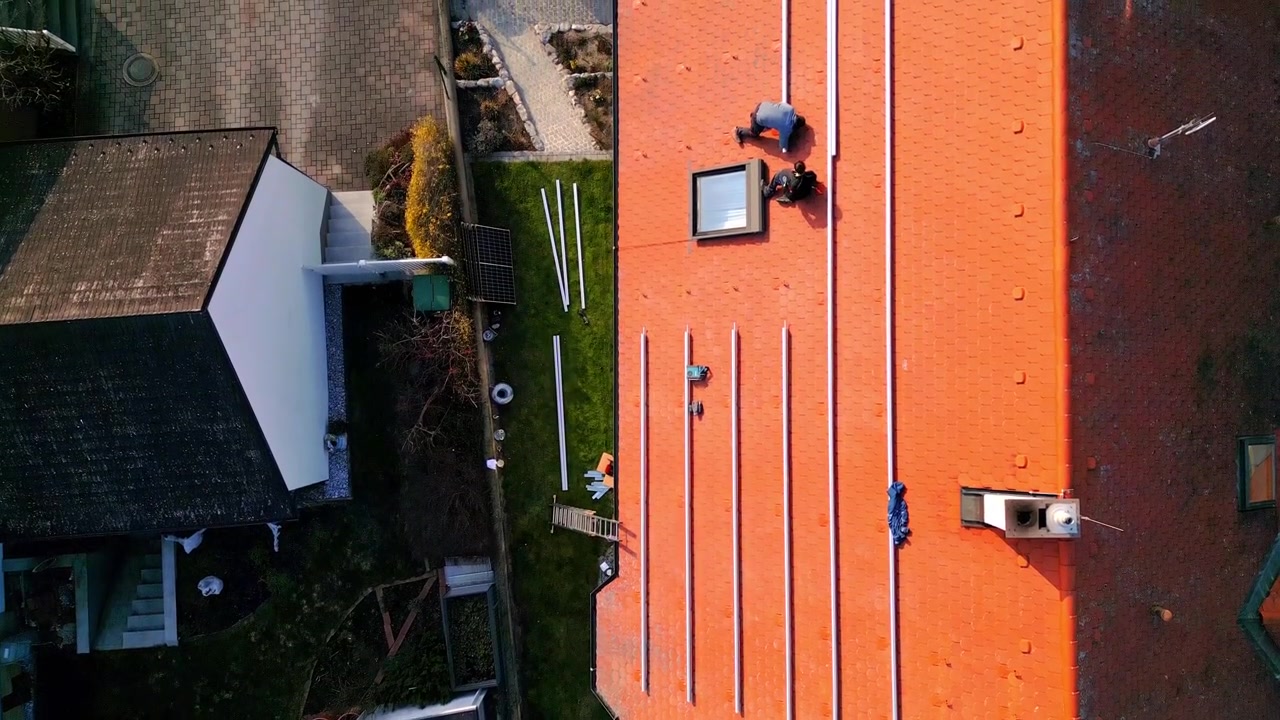 Men At Work Installing Solar Panel Mounting Rails On House Roof. aerial topdown