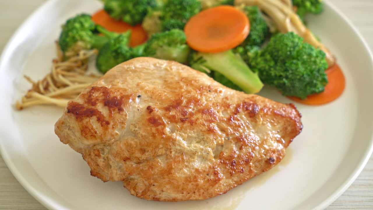 filete de pollo a la parrilla con verduras en un plato blanco