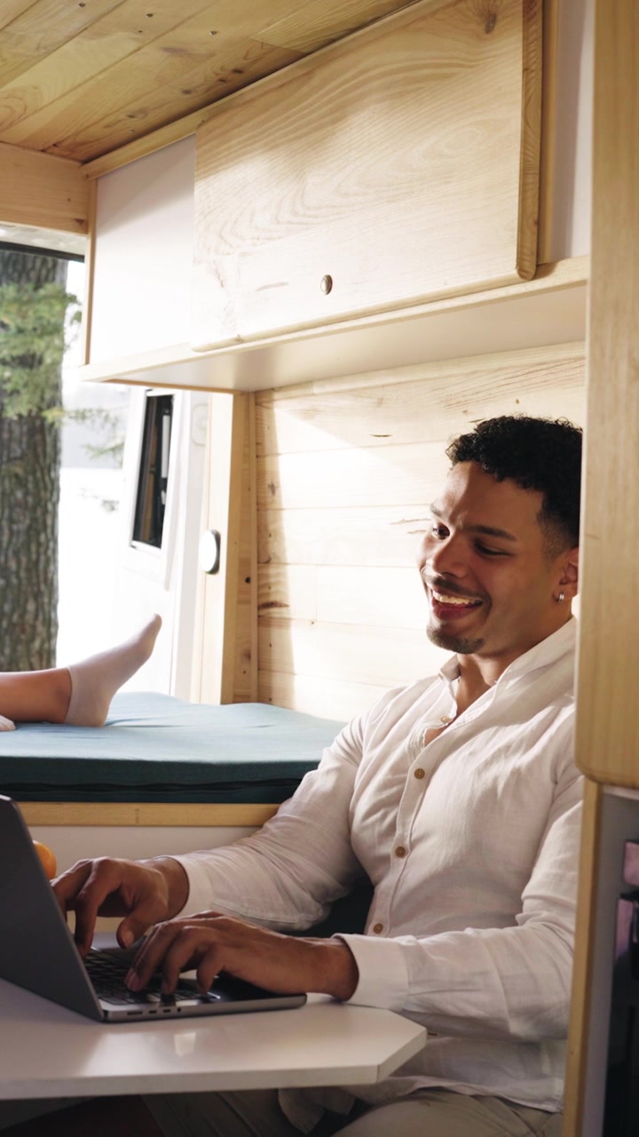 Happy Young Man Working on Laptop Inside a Camper Van