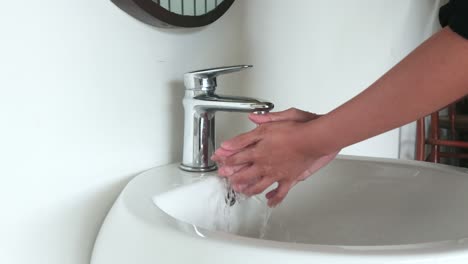 lavarse las manos en un fregadero para lavar la piel y el agua fluye a través de las manos