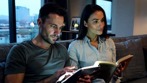 pareja leyendo juntos en el sofá por la noche