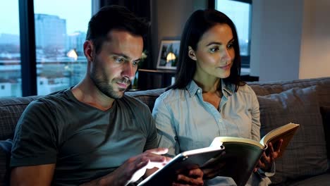 couple reading together on sofa at night