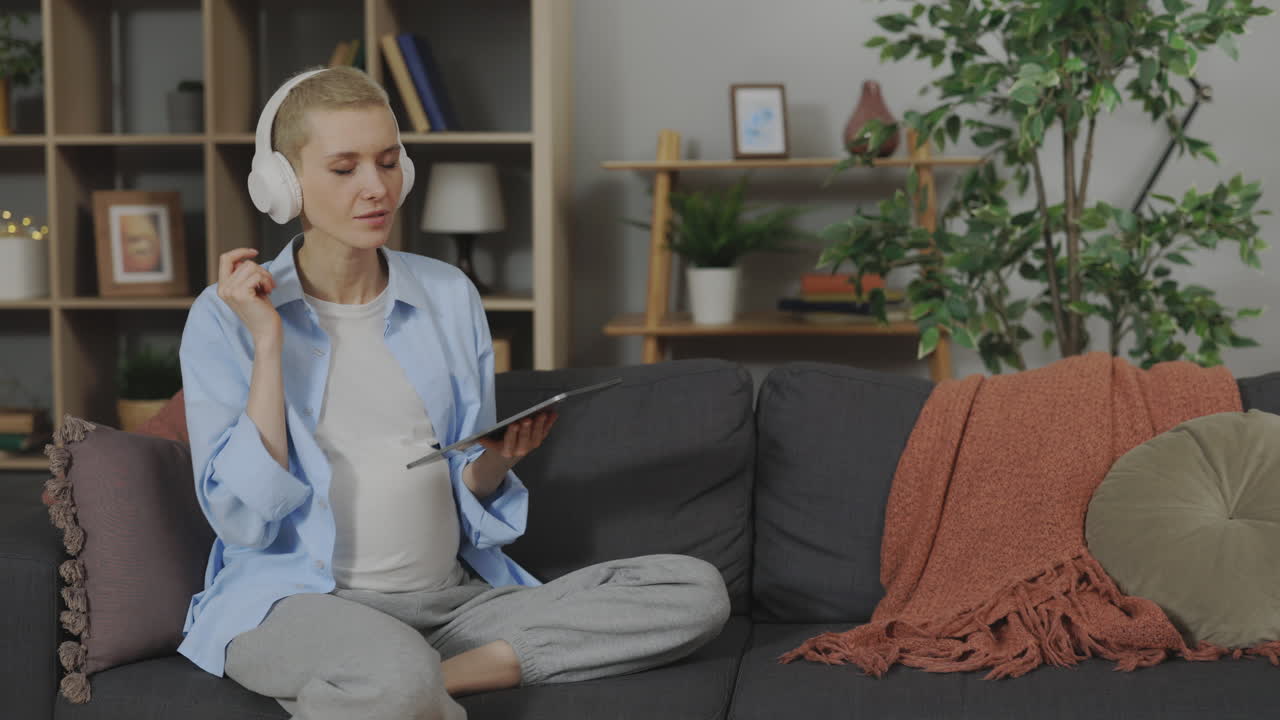 Pregnant Woman Relaxing at Home with Headphones and Tablet
