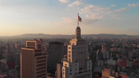 aerial view of altino arantes building, called banespao with the flag fluttering, at sunset, sao paulo downtown, brazil