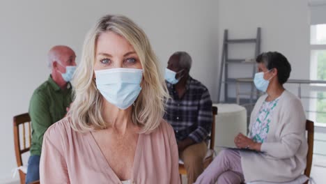 Two-diverse-senior-couples-sitting-in-circle-having-therapy-conversation-at-home-looking-at-camera