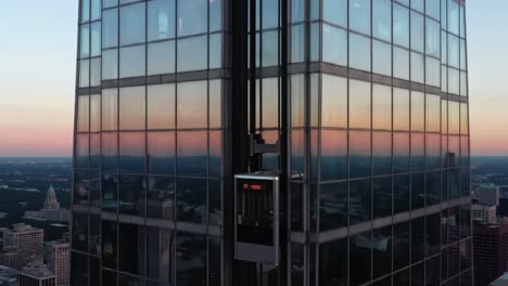 experience breathtaking views from a high-rise building as the elevator ascends towards the skyline during sunset hours, showcasing stunning architecture and city landscape.