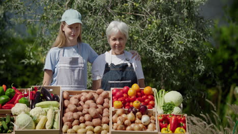 portrait of an elderly farmer woman with her granddaughter. standing behind a vegetable stall at a farmers' market