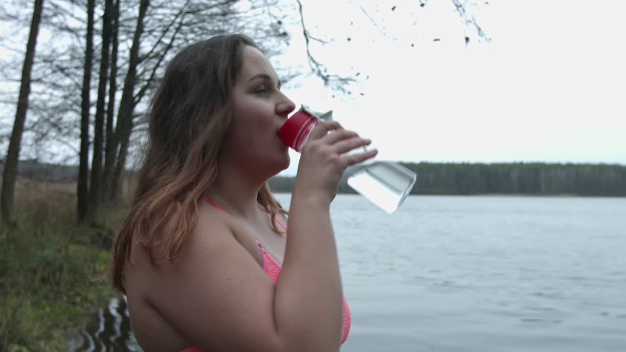 환경 친화적인 비돈에서 운동 후 공원에서 물을 마시는 운동복 여성의 목마른 플러스 사이즈