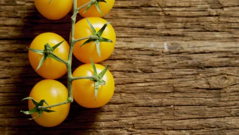 Yellow-cherry-tomatoes-with-stem-on-wooden-floor-4K-4k