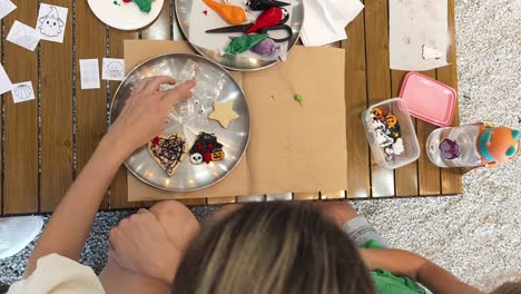 kids decorating halloween cookies with mom