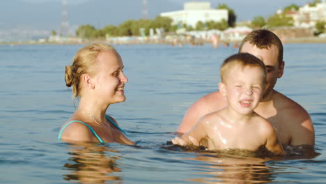 Felices-Padres-E-Hijo-Bañándose-En-El-Mar-En-El-Resort.