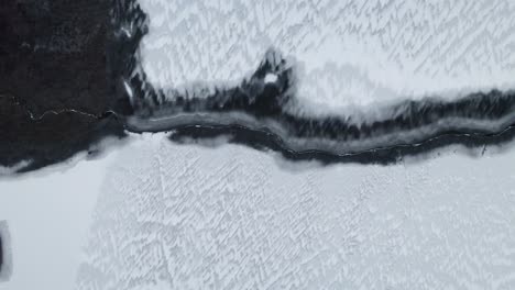 frozen lake and river in cold winter nature scene in poland, aerial top down