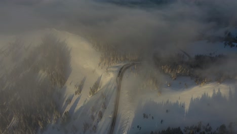 aerial view of misty sunny morning above snow capped mountain hills and peaks