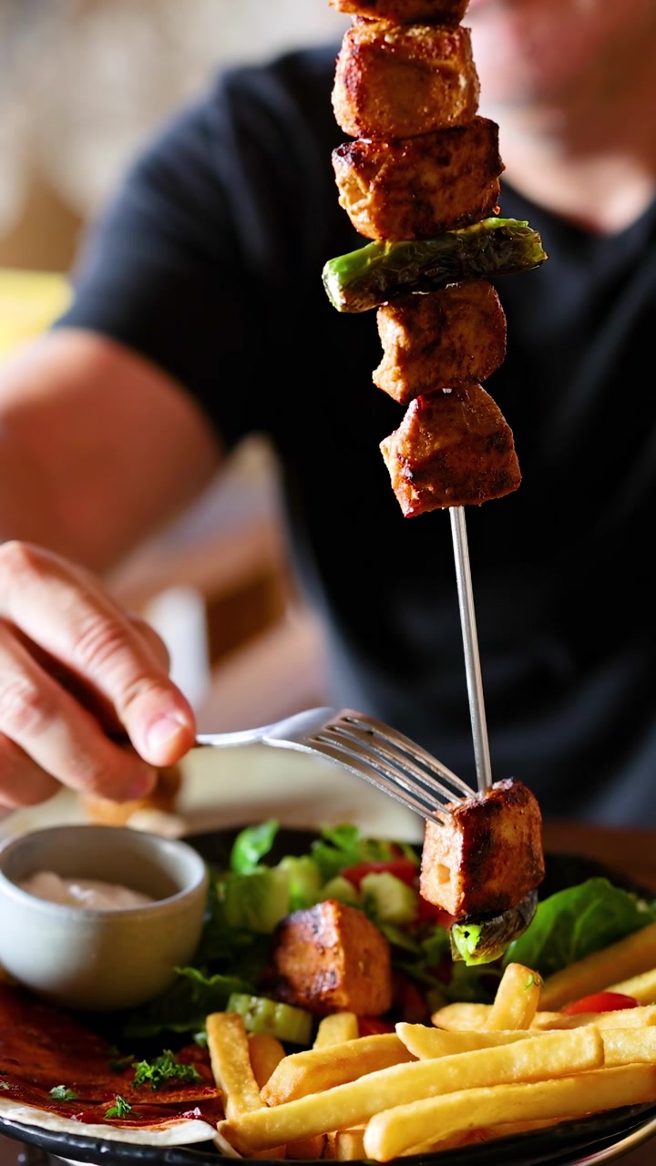 Gustare spiedini di carne e patatine fritte al ristorante