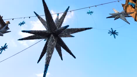 Toma-Inclinada-De-Una-Estrella-Gigante-De-Piñata-Mexicana-Navideña-Con-Edificios-Antiguos-Y-Cielo-Azul-En-El-Fondo.