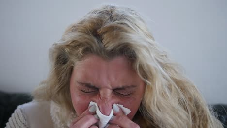 close-up of a sick woman sneezing into a tissue