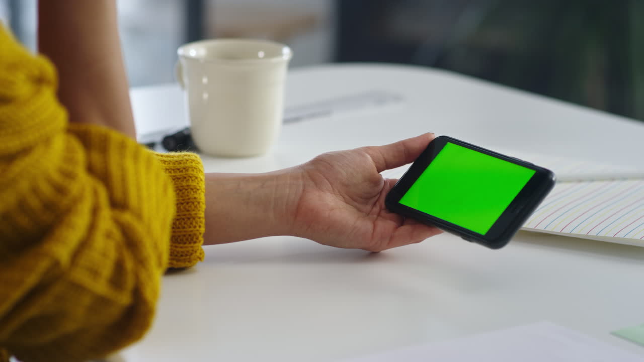 Caucasian woman reading letter on smartphone in office