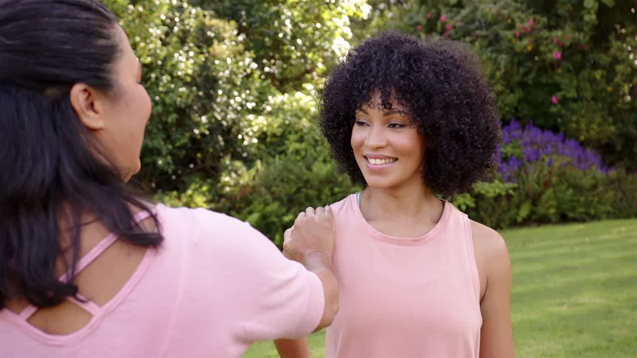 Smiling woman in park, friend placing hand on her shoulder, enjoying conversation