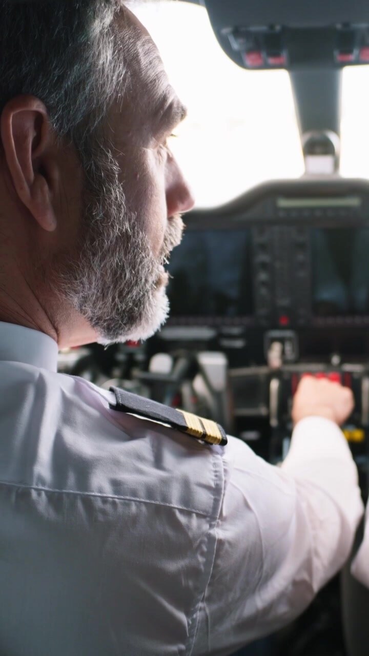 Pilota professionista che aziona i comandi dell'aereo nella cabina di pilotaggio.