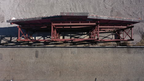 A-top-down-view-of-an-old-building's-red-facade,-supported-by-red-steel-beams