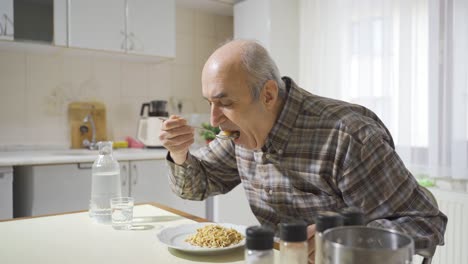 el anciano enfermo come en la cocina.
